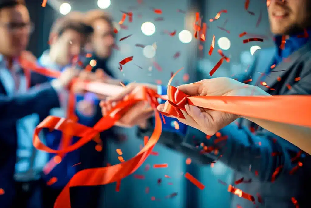 Mains coupant un ruban orange sous une pluie de confettis