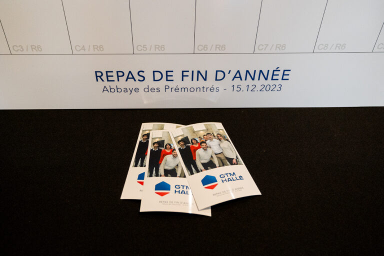 Tirages personnalisés GTM Hallé sortis de la borne selfie, posés devant la trame numérotée du panneau de mosaïque photo