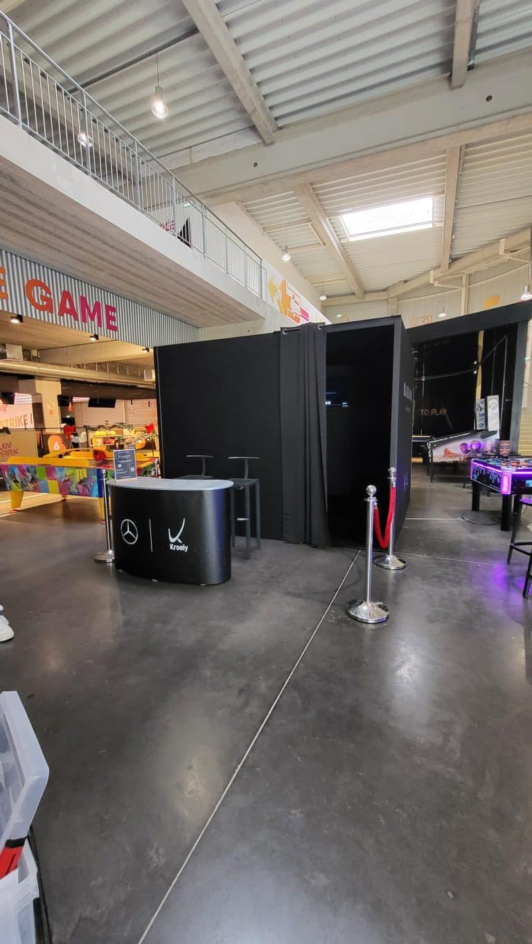 Comptoir d'accueil Mercedes-Benz Kroely, tabourets et rideau noir à l'entrée de la Black Box, dans un complexe de loisirs