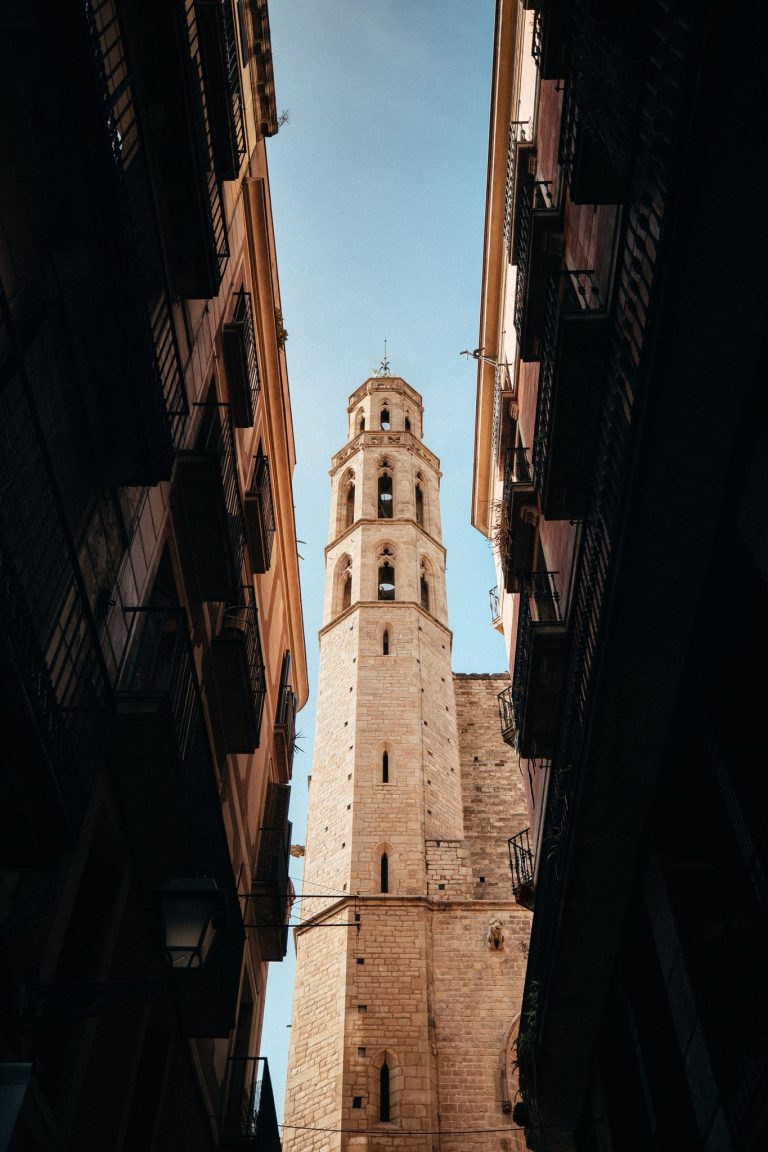 Clocher en pierre de Barcelone vu depuis une ruelle étroite, entre deux façades sombres