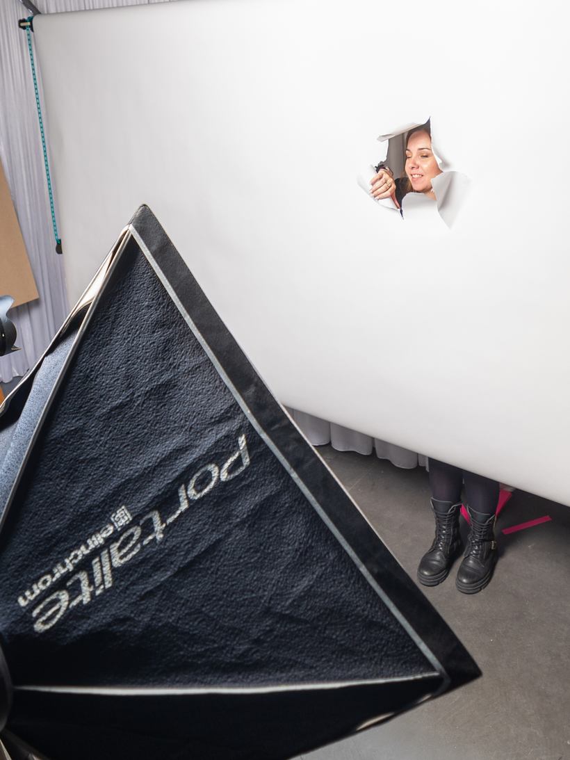 Le visage d'une invitée apparaît dans le fond blanc déchiré du studio photo monté en soirée