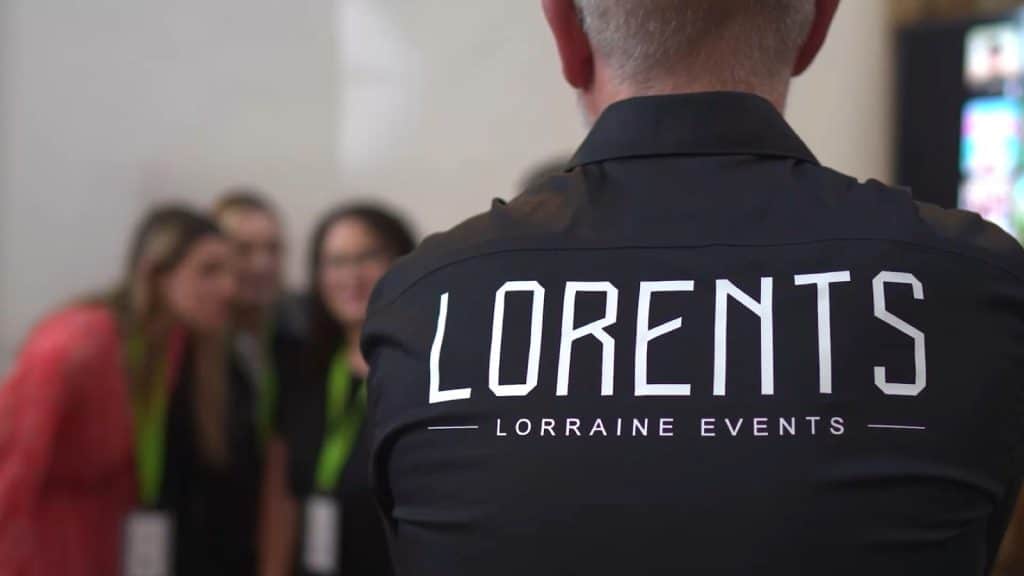 Un membre de l'équipe LORENTS, chemise siglée, face aux invités d'un événement