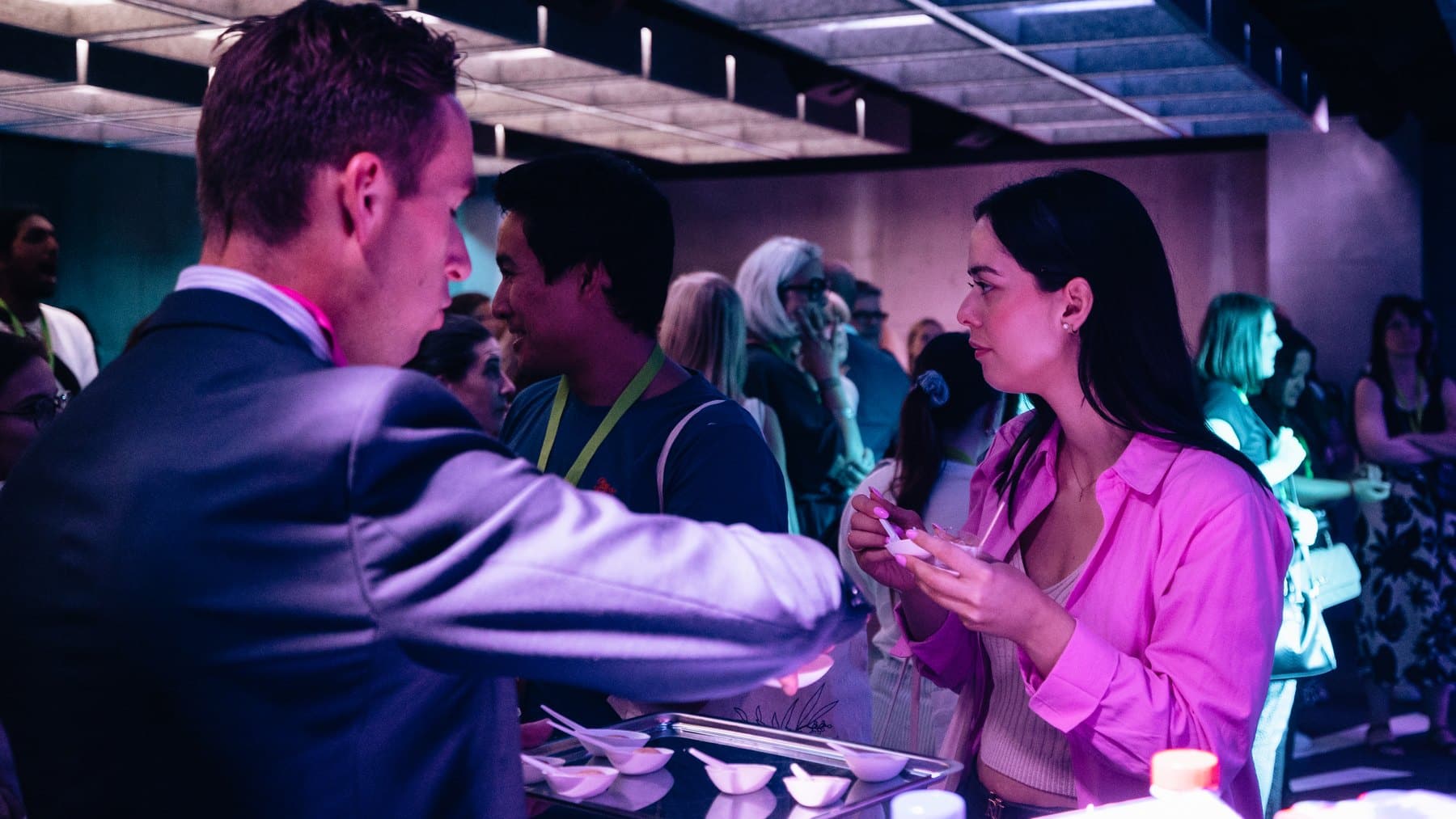 Une invitée en chemise rose échange au buffet d'un cocktail d'entreprise au Rex Club