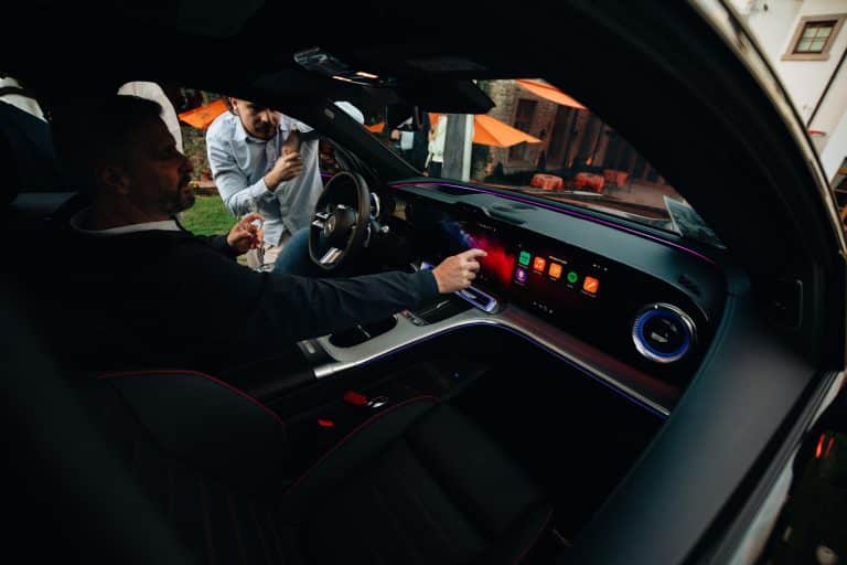 Invité installé au volant d'une Mercedes, la main sur l'écran central, pendant la soirée des nouveautés Kroely