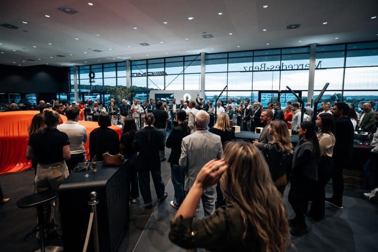 Une centaine d'invités dans le showroom Mercedes-Benz Kroely de Metz, voiture sous housse orange au premier plan