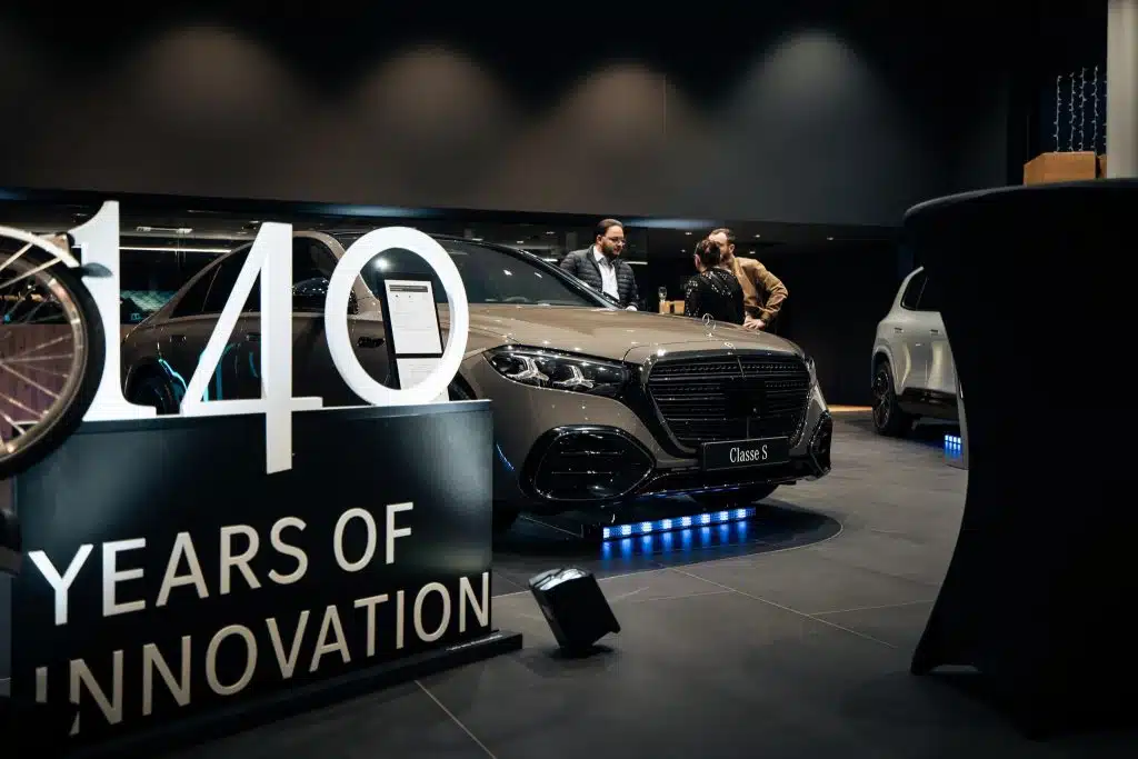 Mercedes Classe S grise sur le podium du showroom Kroely de Metz, halo LED bleu au sol, panneau « 140 years of innovation » au premier plan