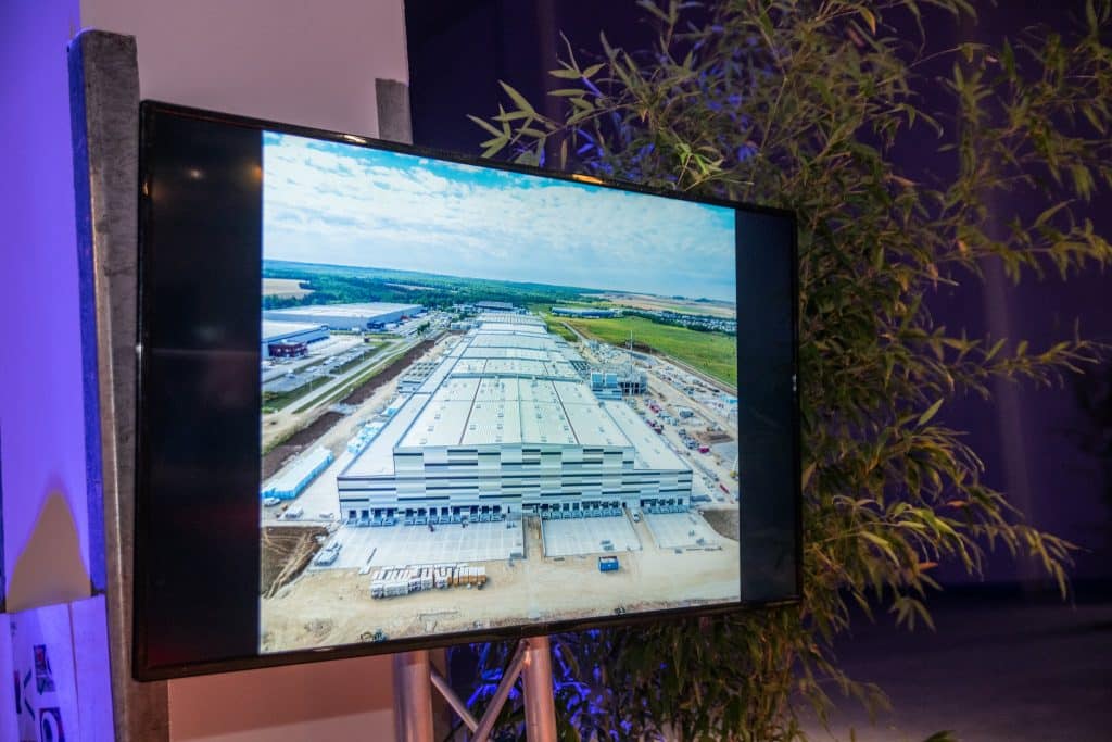 Écran diffusant une vue aérienne de la plateforme logistique en construction