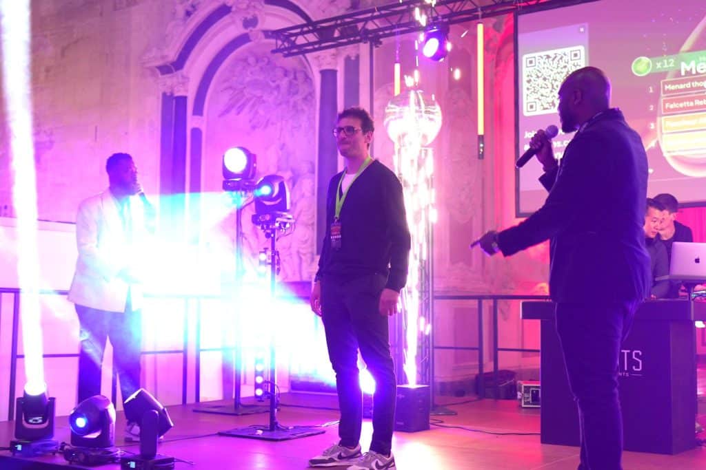 Jonas au micro sur scène, sous les faisceaux lumineux, avec l’équipe LORENTS