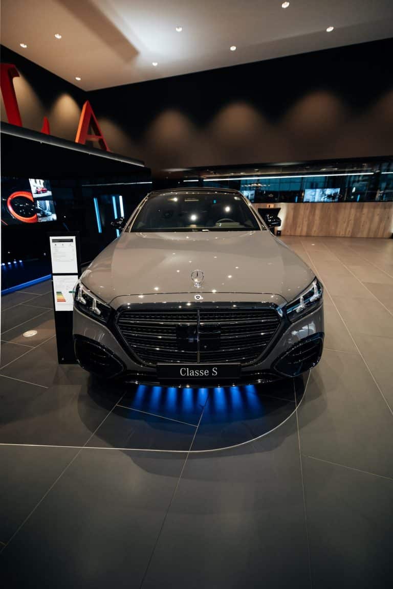 Face avant de la Mercedes Classe S grise, calandre étoilée, barre LED bleue posée au sol sous le pare-chocs, showroom Kroely Metz