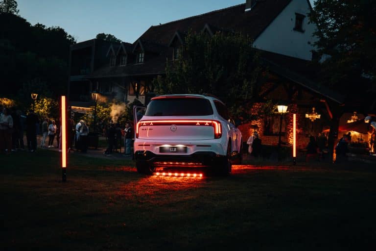 Mercedes GLB blanc vu de l'arrière, barre LED orangée au sol et deux tubes LED Pixtube, devant l'Auberge Saint-Walfrid à la tombée de la nuit