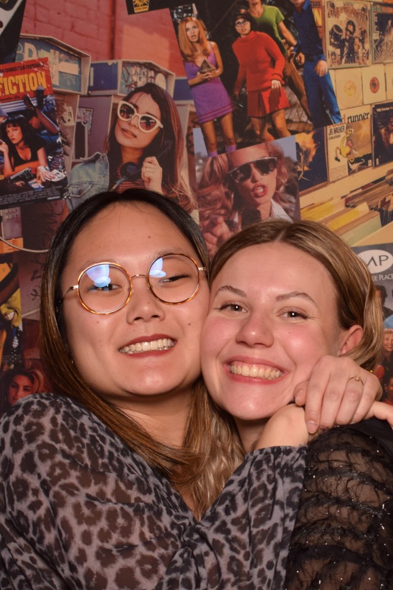 Deux invitées joue contre joue devant le mur photo