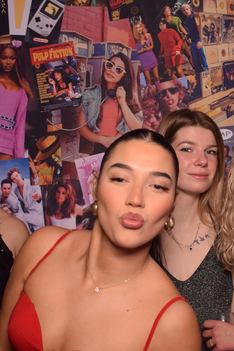 Une invitée en robe rouge prend la pose devant le photocall