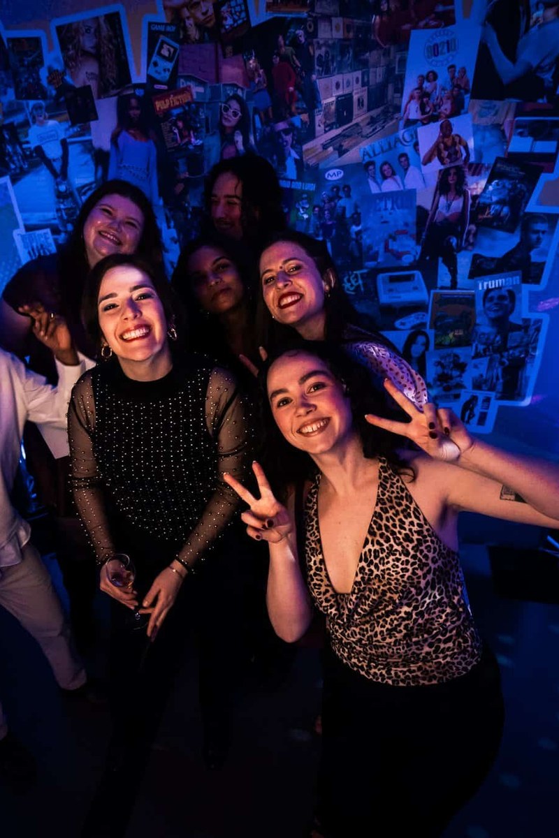 Trois invitées font le V de la victoire devant le mur de photos éclairé en bleu