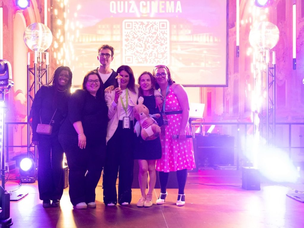 Équipe gagnante du Quiz Cinéma sur scène, trophée en main, sous les étincelles froides