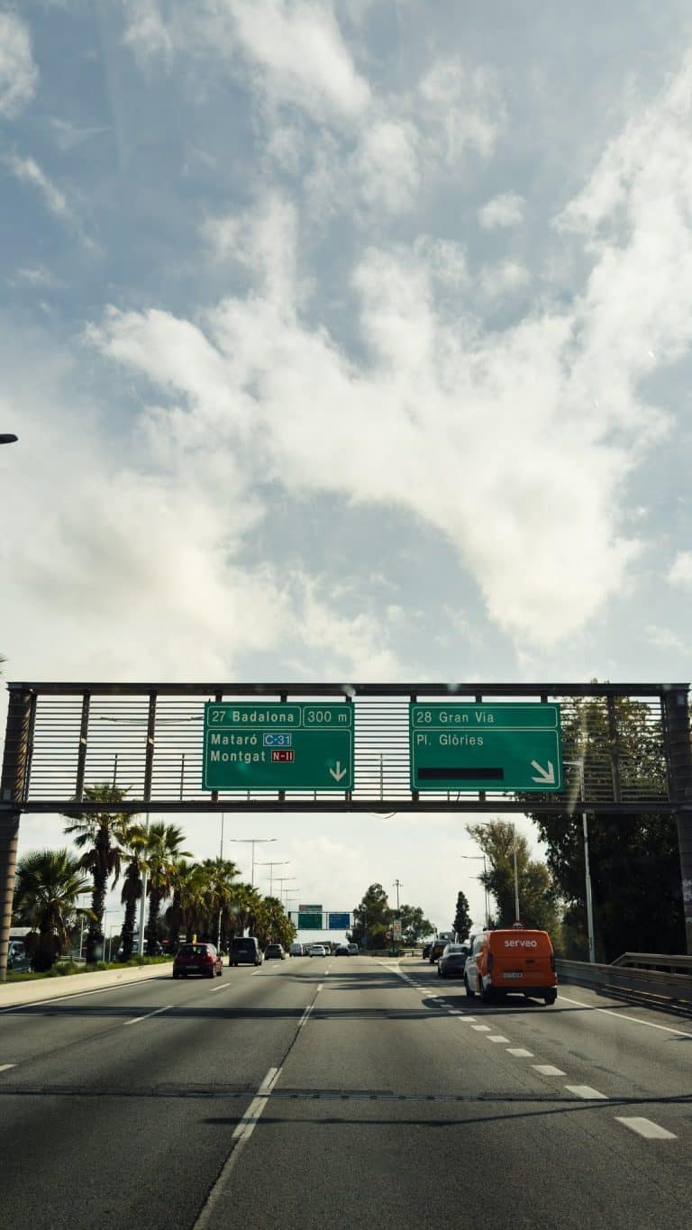 Autoroute espagnole sous un ciel voilé, panneaux de direction vers Girona et la France