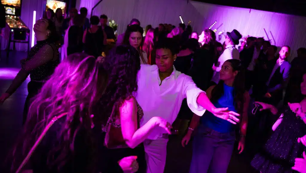 Des invités dansent sur la piste d'une soirée privée, mise en lumière violette LORENTS