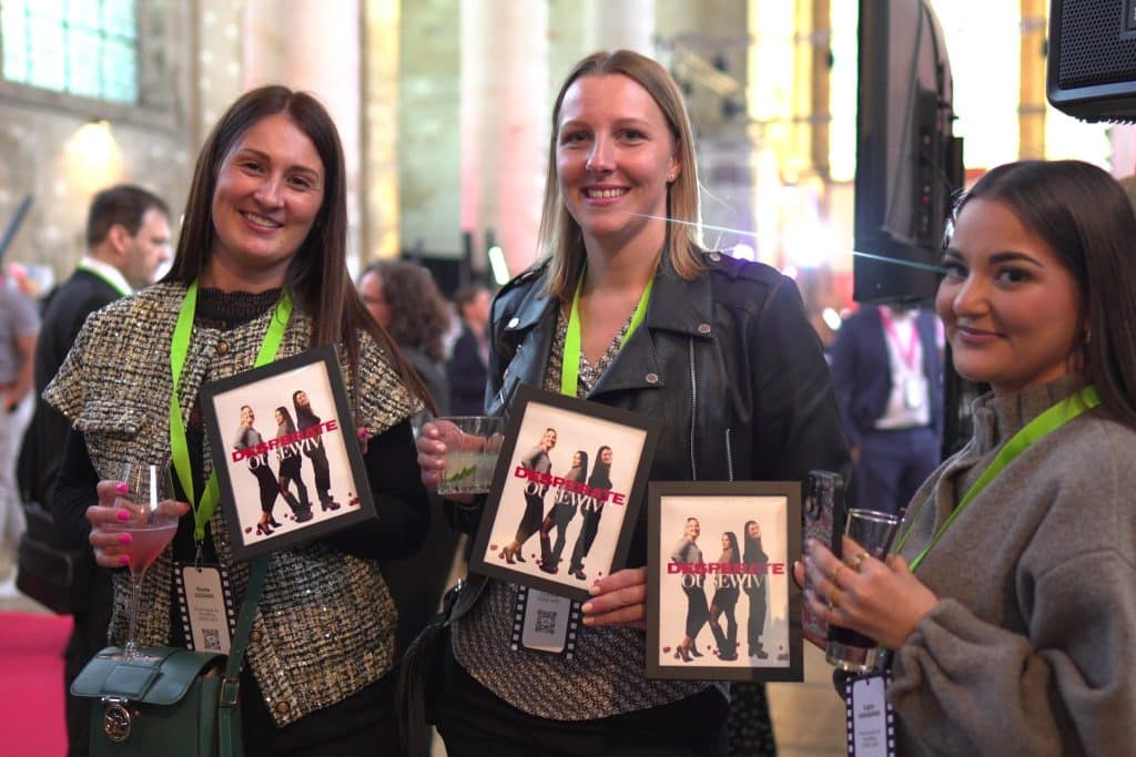 Trois invitées souriantes tiennent chacune leur tirage encadré au milieu du salon