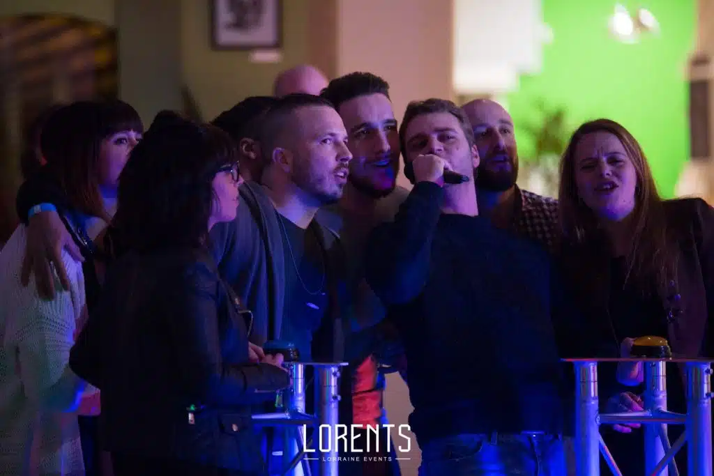 Une équipe serrée derrière son buzzer répond au micro pendant Touche pas à mes jeux télé, soirée CE Alinéa à Nancy